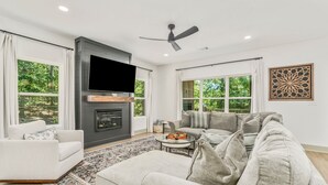 Una sala de estar moderna con chimenea, televisor de pantalla plana, sofá gris y una mesa de centro.