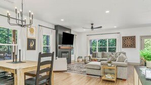Una sala de estar moderna con chimenea, un comedor con mesa y sillas de madera, y una zona de estar con sofá y sillones.
