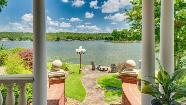 A patio with a stone pathway, outdoor furniture, and a view of a lake. - Beautiful Balboa Lake Home with Stunning View (Hot Springs Village)