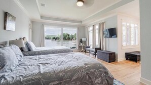 A bedroom with two beds, a TV, a desk, and a view of the outdoors. - Beautiful Balboa Lake Home with Stunning View (Hot Springs Village)