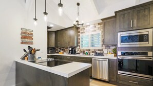 Una cocina moderna con una isla central, electrodomésticos de acero inoxidable y armarios de madera.