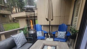 Un patio al aire libre con una chimenea, zona de estar y un pérgola.