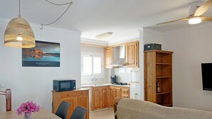 Une cuisine moderne avec des meubles en bois, un four à micro-ondes encastré et un coin repas comprenant une table et des chaises.