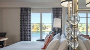 Une chambre d’hôtel avec un lit, un bureau et une vue sur une piscine et des arbres.