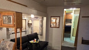 A compact room with a sofa, a wooden chair, a small table, and a mirror on the wall.