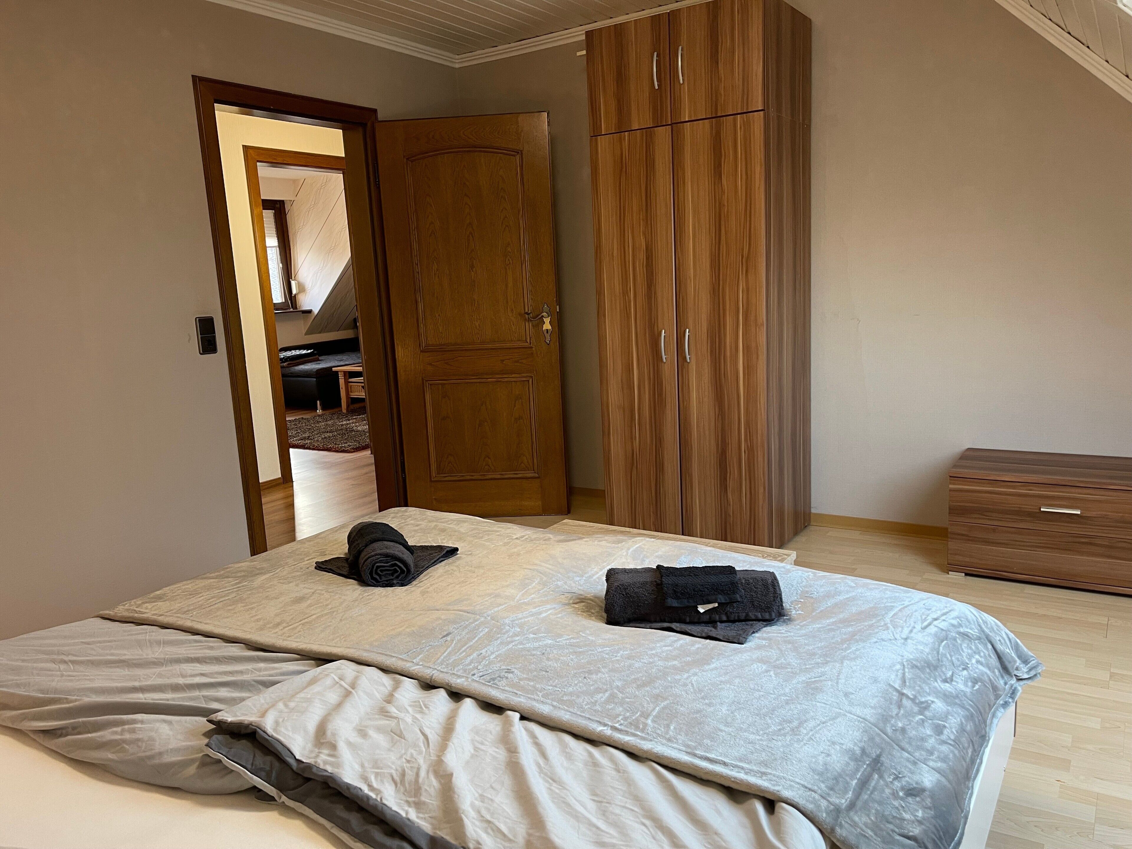 A bedroom with a bed, a wardrobe, and a small wooden dresser.