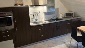 Eine moderne Küche mit dunklen Schränken, Edelstahlgeräten, einer eingebauten Mikrowelle und einem Fenster über der Spüle.