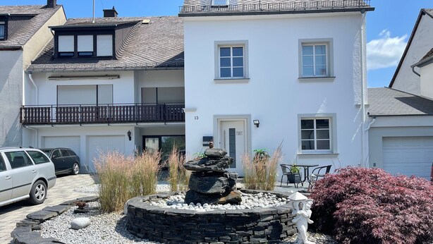 Ein zweistöckiges Haus mit einem Steingarten, einem Balkon und einer Garage.