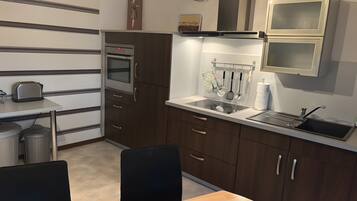 A compact kitchen with a built-in oven, a sink, and a small dining area with a table and chairs.