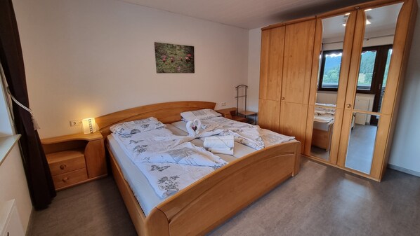 Un dormitorio con cama de madera, mesita de noche, espejo y armario.