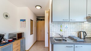 Pieni, käytännöllinen keittiö, jossa on mikroaaltouuni, pesuallas ja kaapistot.