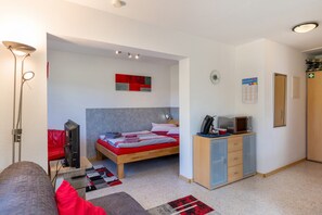 A modern bedroom with a bed, bedside table, lamp, and a small desk with a computer.