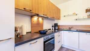 A modern kitchen with wooden cabinets, a stove, and a sink.