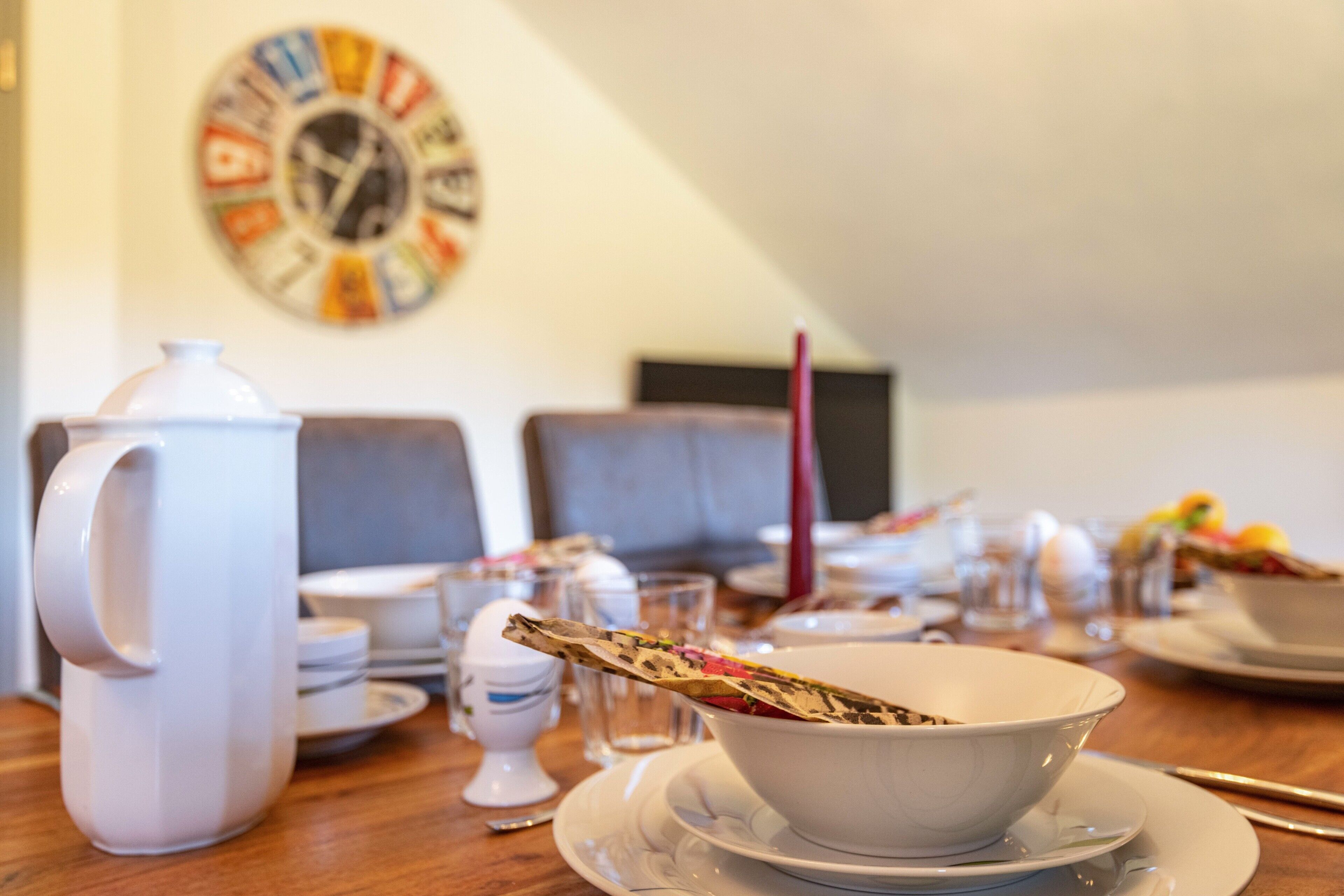 A dining table set with plates, bowls, a pitcher, and glasses.