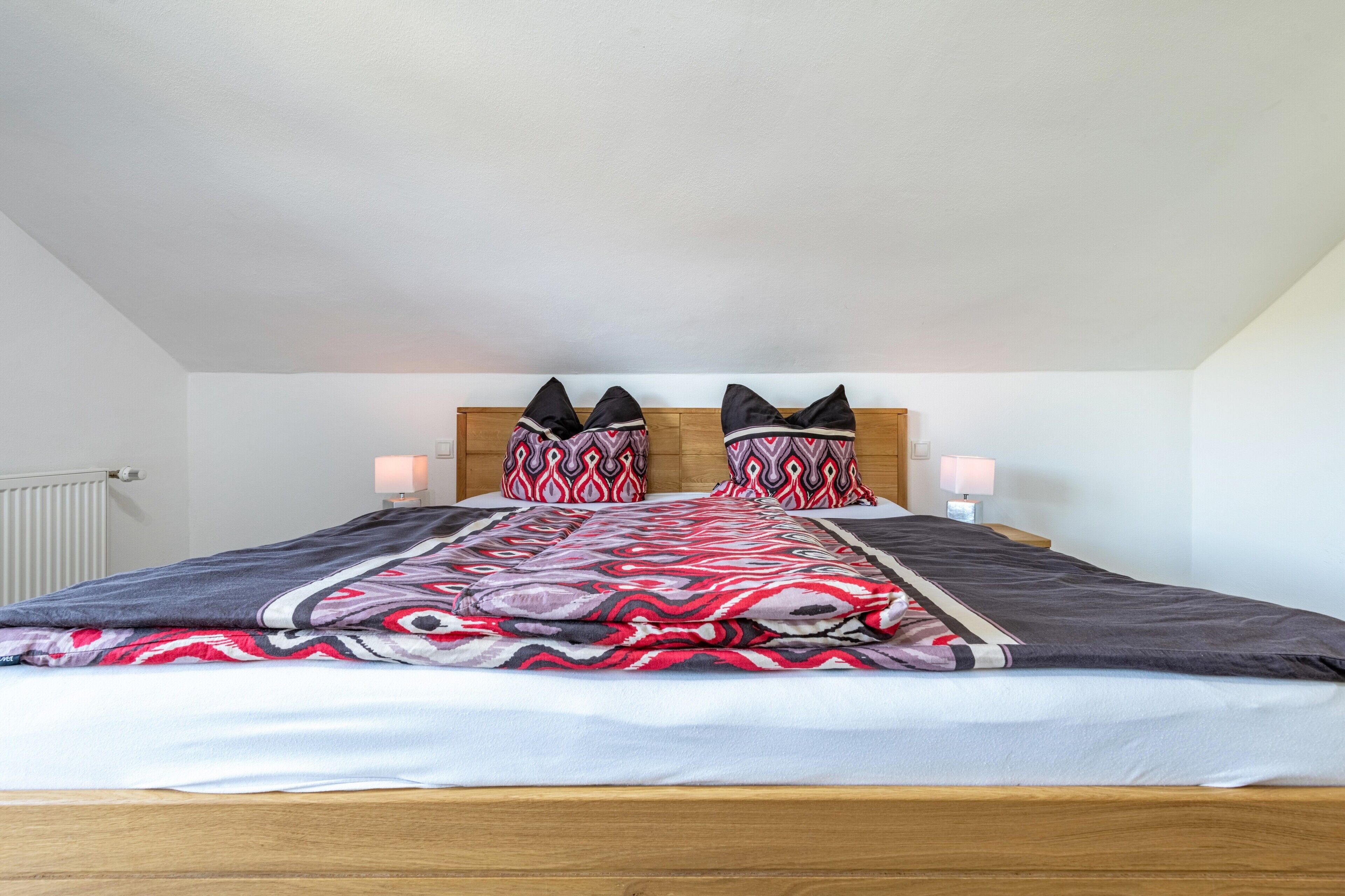 Quarto com cama, duas luminárias de cabeceira e encosto de cama.