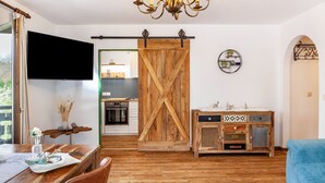 Una cocina moderna con televisor, puerta corredera de madera y un mueble rústico.