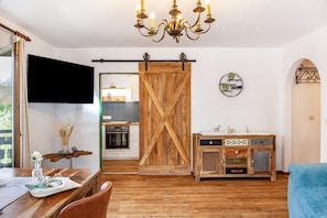 Una cocina moderna con televisor, puerta corredera de madera y un mueble rústico.