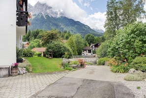 A paved driveway leading to a building with a mountain backdrop.