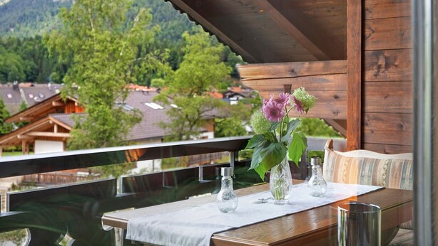 A wooden balcony with a table, two vases, and a bench. - Studio Apartment 'Aschaubichl - Anemone' with Mountain View, Balcony and Wi-Fi (Grainau)