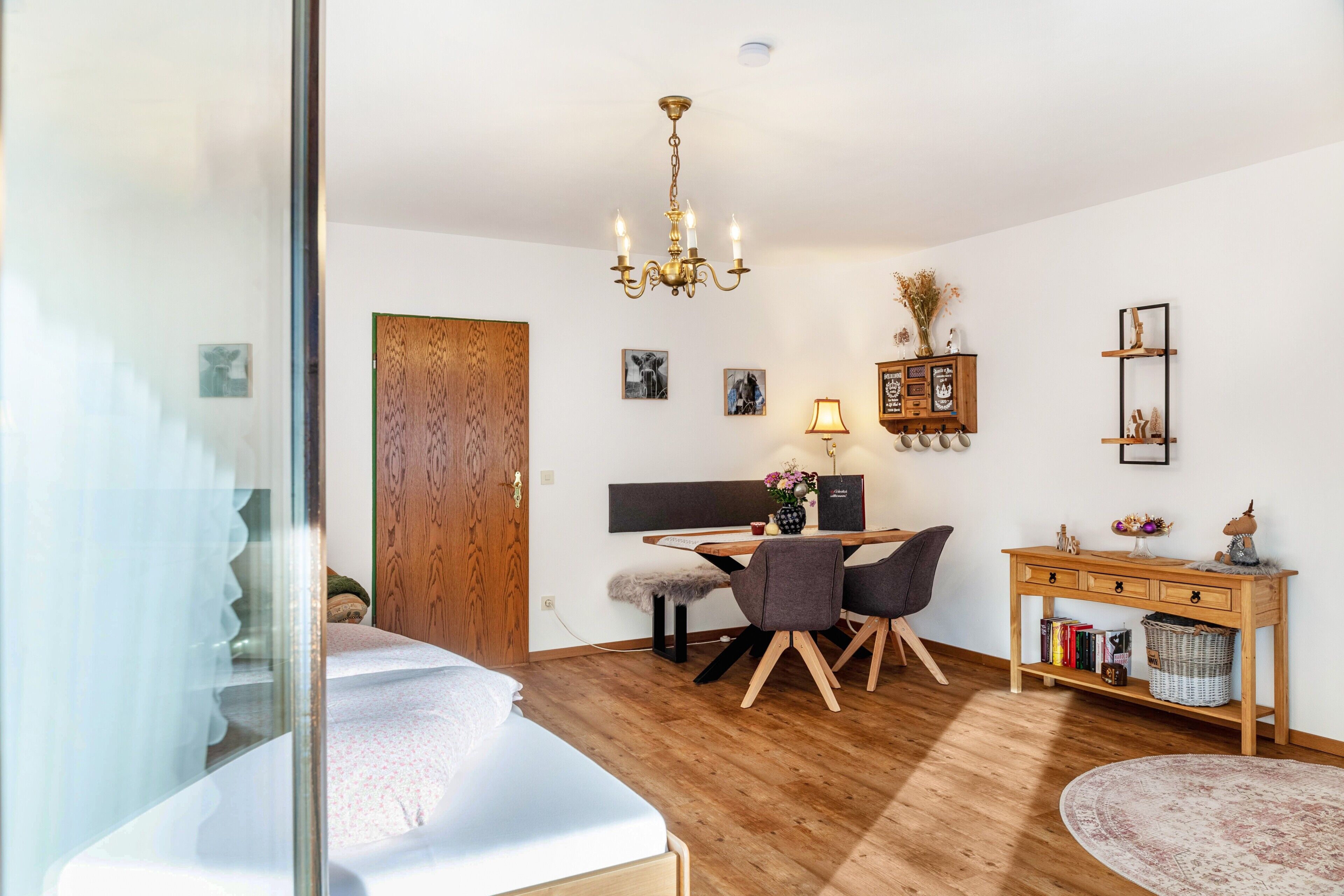 Un dormitorio con cama, escritorio, silla, aparador de madera y candelabro.