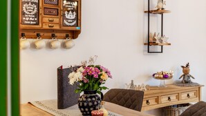 Ein Essbereich mit einem Holztisch, einer Blumenvase, einem dekorativen Schrank und einem Regal mit kleinen Figuren.