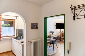 Une cuisine avec une fenêtre, un radiateur, un évier et un coin repas comprenant une table et des chaises.