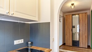 A modern kitchen with a built-in stove, grey tiles, and white cabinets.