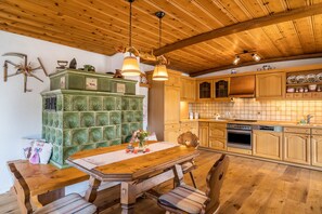 Una mesa de comedor de madera con sillas, un mueble verde, armarios de madera y un salpicadero de azulejos en una cocina.