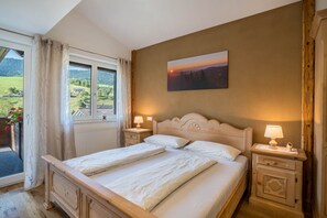 Una cama doble con cabecera, mesitas de noche con lámparas, una ventana con cortinas y un cuadro en la pared.