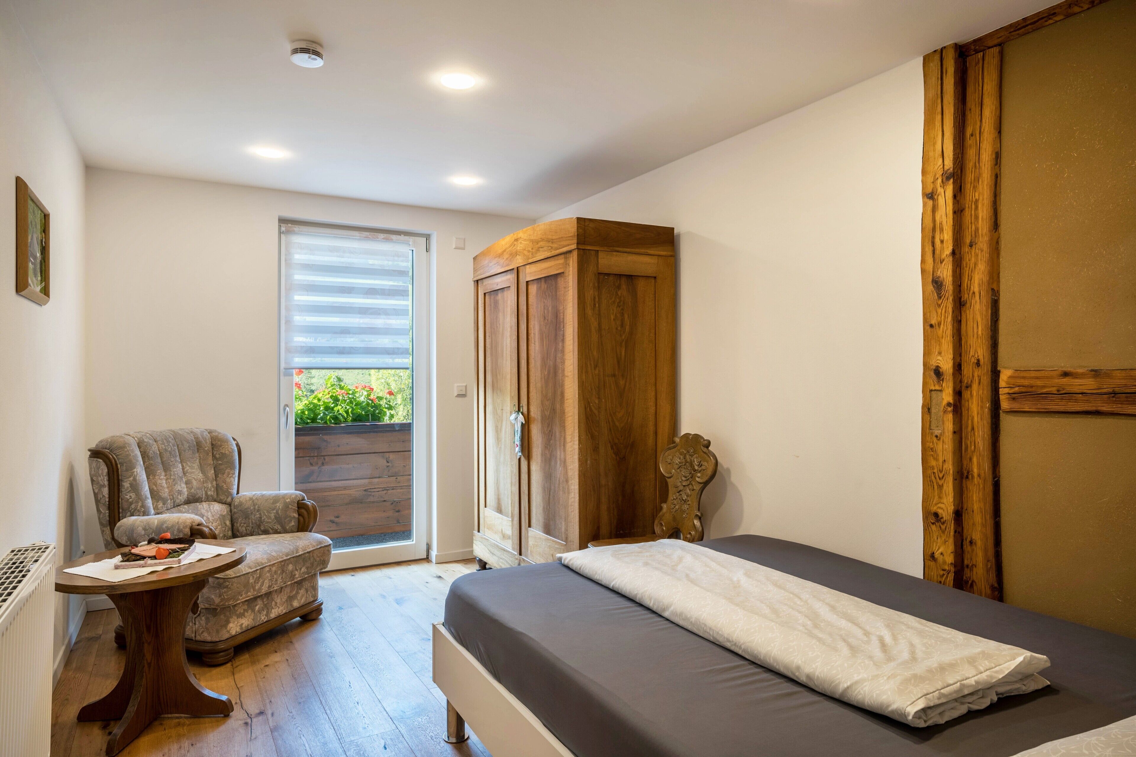 Une chambre à coucher avec un lit, une chaise, une table et une armoire.