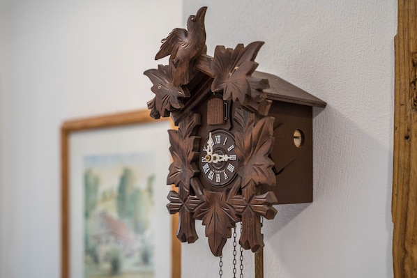 A wooden cuckoo clock with a bird and floral design, mounted on a wall.