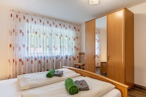 Een hotelkamer met twee bedden, een houten garderobe en een spiegel.