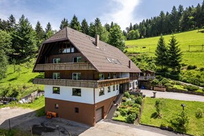 A multi-story chalet with a sloped roof, wooden balconies, and a stone foundation. - Holiday Apartment "Fuchsmichelhof 4" with Mountain View, Private Terrace & Wi-Fi (Seebach)
