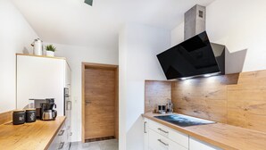 Een moderne keuken met een houten aanrecht, witte kasten en een ingebouwde magnetron.
