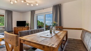Een moderne eetruimte met een houten tafel, stoelen en een bank.