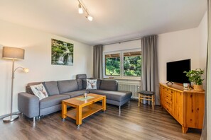 A modern living room with a grey sofa, wooden coffee table, and a wooden cabinet with a television. - Holiday Apartment "Fuchsmichelhof 4" with Mountain View, Private Terrace & Wi-Fi (Seebach)