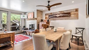 A dining area with a wooden table, six chairs, a ceiling fan, and a fireplace. - Perfect Location Between Vail & Loinshead (Vail)
