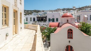 Un edificio blanco con una cúpula roja, un balcón y vistas a un pueblo con edificios blancos y una colina al fondo.