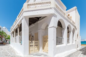 Ein weißes Gebäude mit überdachter Veranda, einer gepflasterten Straße und Blick auf das Meer.