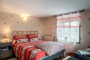 Une chambre à coucher avec un lit, une table de chevet, une lampe et une fenêtre avec des rideaux.