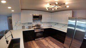 Una cocina moderna con un refrigerador de acero inoxidable, horno empotrado y microondas.