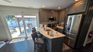 A modern kitchen with a central island, stainless steel appliances, and a view to the outside. - The Perfect Escape with Gorgeous Heated In-Ground Pool (Lower Township)