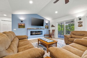 A living room with a fireplace, a flat-screen TV, and a large window.