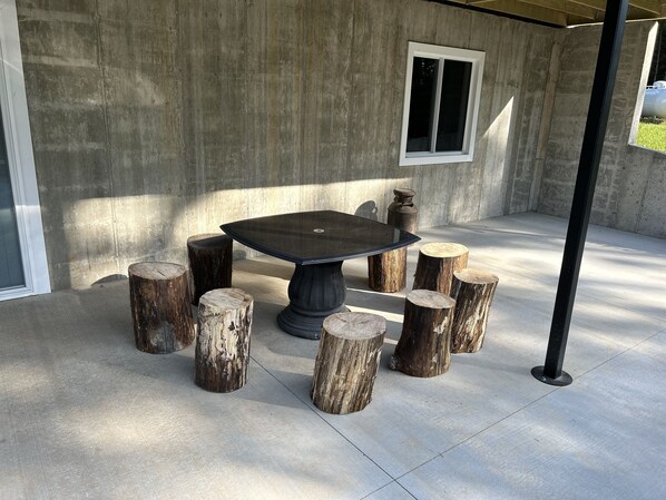 A concrete patio with a round table and wooden stools.