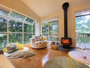 Una sala de estar acogedora con chimenea, ventanas amplias y un espacio de estar confortable.