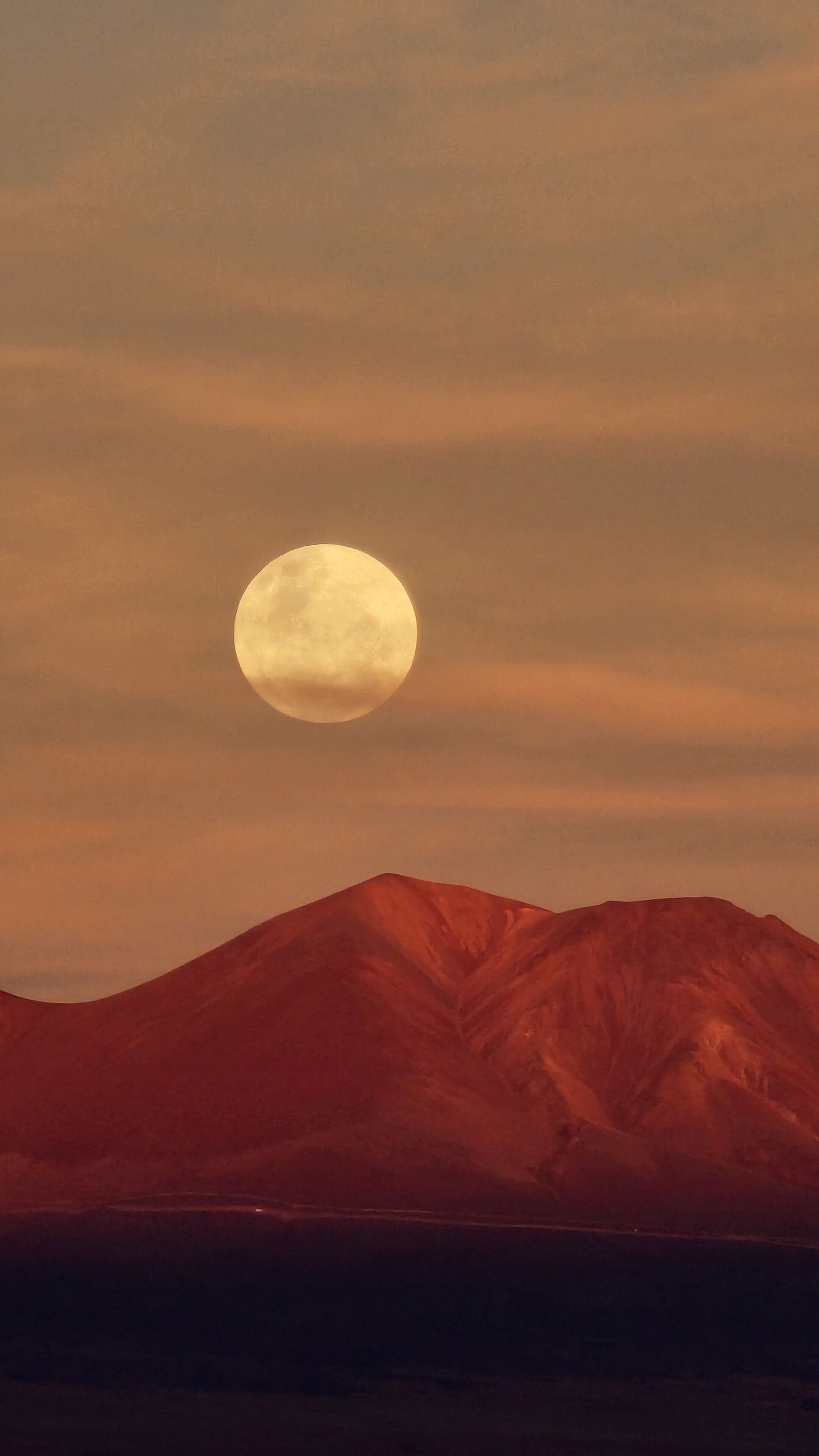 Una cordillera con una luna llena en el cielo.