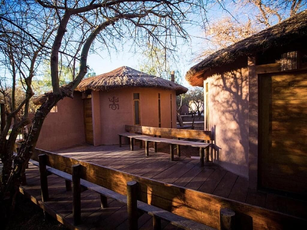 A rustic building with a thatched roof, wooden benches, and a wooden deck.