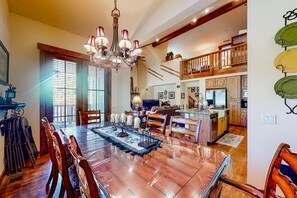 Experience a homey atmosphere in this well-appointed space, featuring a large dining table, modern chandelier, and cozy seating area.