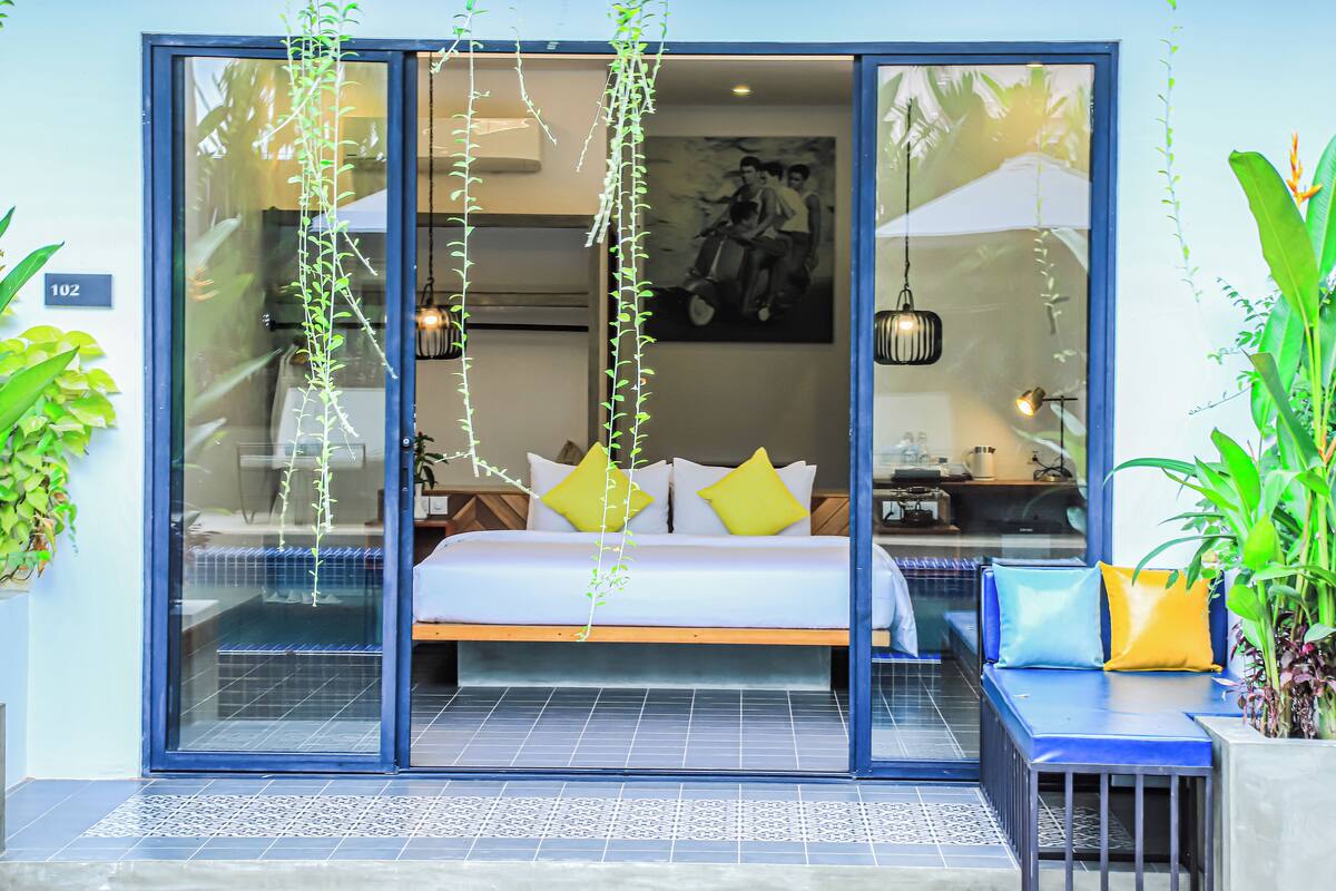 A modern hotel room with a bed, a seating area, and a dining space.