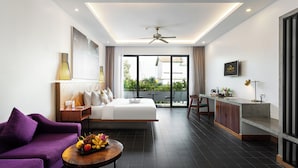 Ein modernes Hotelzimmer mit einem großen Bett, einem violetten Sofa, einer Essecke und einem Balkon mit Blick.